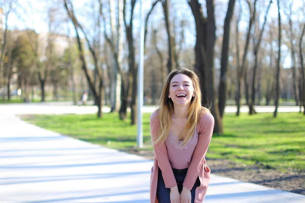 Gadis lucu tertawa, melihat kamera dan berjalan di taman musim semi . — Stok Foto