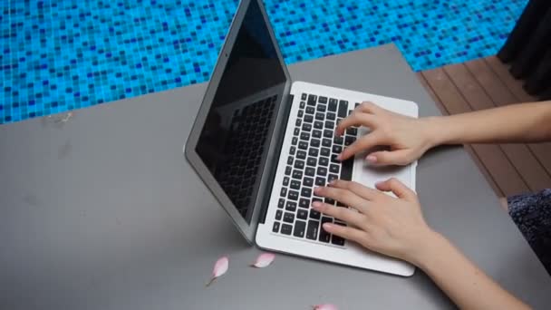 Stäng upp händer att skriva på laptop tangentbord i slow motion nära poolen. — Stockvideo