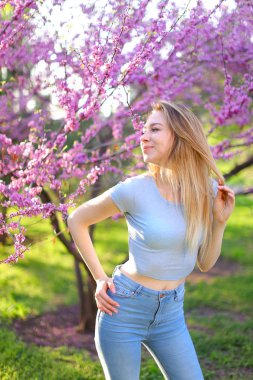 Sarışın kadın fotoğraf modeli ayakta çiçeği arka plan ile parkta.