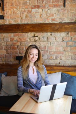 Güzel erkek beyaz dizüstü bilgisayar ve samimi kafede kahve ahşap masa oturma.