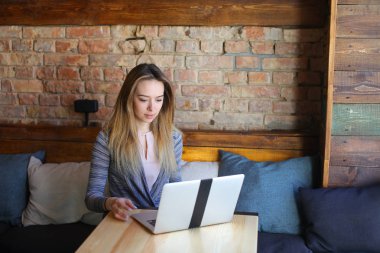 Rahat coffee House tablo cam fincan kapuçino ve dizüstü bilgisayar kullanarak sohbet ile yakın oturan genç kadın.
