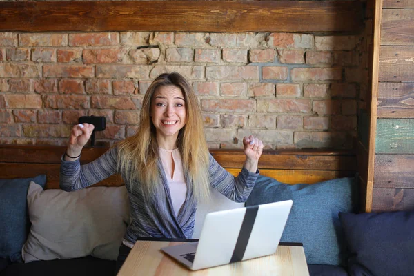 Chica feliz disfrutando de ganar apuestas en línea cerca del ordenador portátil . — Foto de Stock