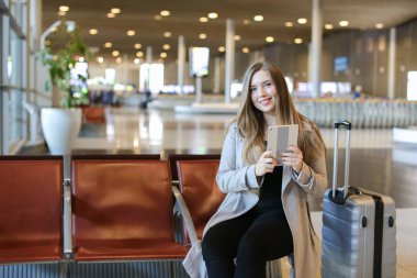 Havaalanı hall yanında valiz tablet ile internet kullanan Avrupa kız.