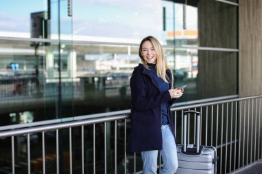 Smartphone ve valiz yakınındaki kalacak güzel kadın.