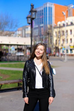 Şehirde yürüyüş ve deri ceket giyiyor büyüleyici kadın.