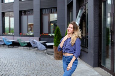 Bina ve mavi gömlek ile kot giyen yakın duran genç kadın kişi.