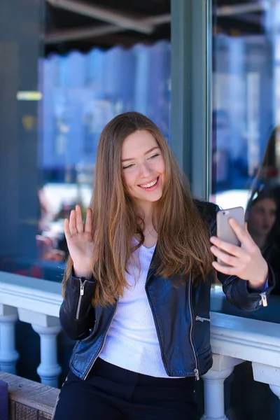 Дівчина робить відеодзвінок за допомогою смартфона в кафе . — стокове фото