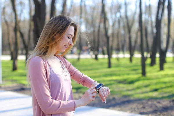 Chica caminando en el parque y usando reloj inteligente . — Foto de Stock