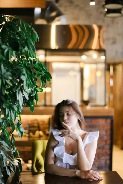 Vacker ung kvinnlig person vilar på café och bär vit blus med silver ring. — Stockfoto