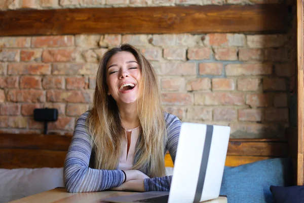 Riéndose chica utilizando Internet por ordenador portátil en la cafetería . — Foto de Stock