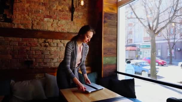 Hermosa mujer visitando la cafetería con el ordenador portátil y disfrutando de charlar en red social . — Vídeos de Stock