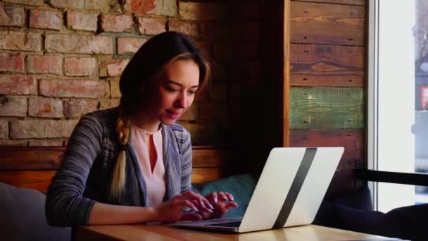 Mujer bonita se familiariza con la persona masculina por Internet utilizando el ordenador portátil en la cafetería . — Vídeos de Stock