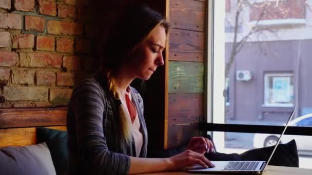 Estudante do sexo feminino que digita o curso por laptop no café . — Vídeo de Stock
