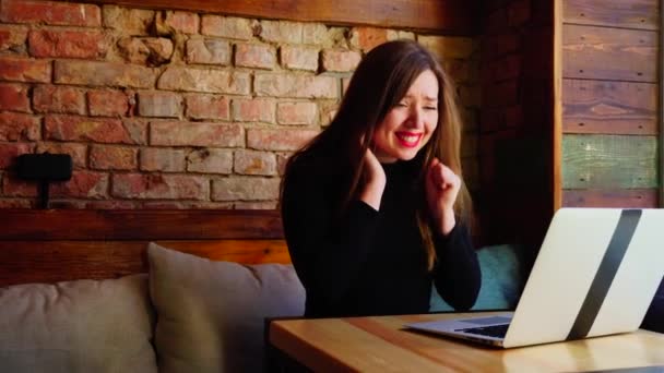 Счастливая женщина выигрывает ставки онлайн на ноутбуке в кафе возле кирпичной стены . — стоковое видео