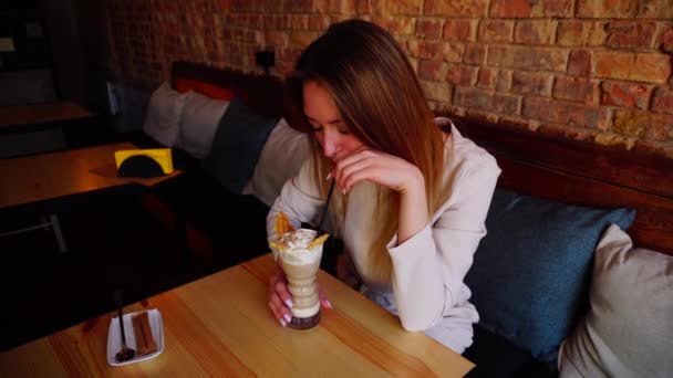 Όμορφο κορίτσι πόσιμο παγωτό κοκτέιλ στο εστιατόριο. — Αρχείο Βίντεο
