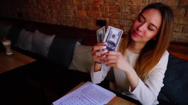 Joven mujer manteniendo las cuentas en las manos, trabajando con papeles y mostrando los pulgares en la cafetería . — Vídeo de stock