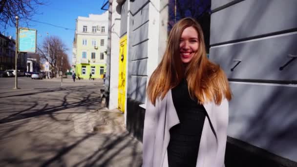 Mosolygó lány séta a város szürke kabátot és fekete ruha. — Stock videók
