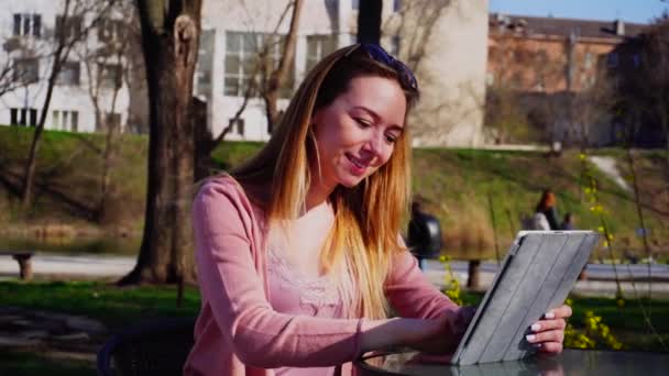 Hermosa persona femenina charlando con amigos por tableta en el parque . — Vídeo de stock