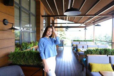 Kot gömlek giymiş ile smartpone, sokak kafede duran beyaz genç kadın.