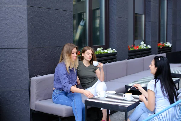 Amigas bebiendo café y sentadas en la cafetería . — Foto de Stock