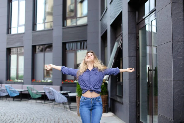 Chica joven disfrutando de caminar en la ciudad y de pie cerca del edificio . — Foto de Stock