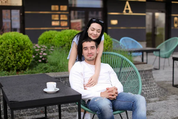 Ευτυχισμένος αγκαλιάζει η σύζυγος κάθεται στην καρέκλα στην καφετέρια του δρόμου έξω από το. — Φωτογραφία Αρχείου