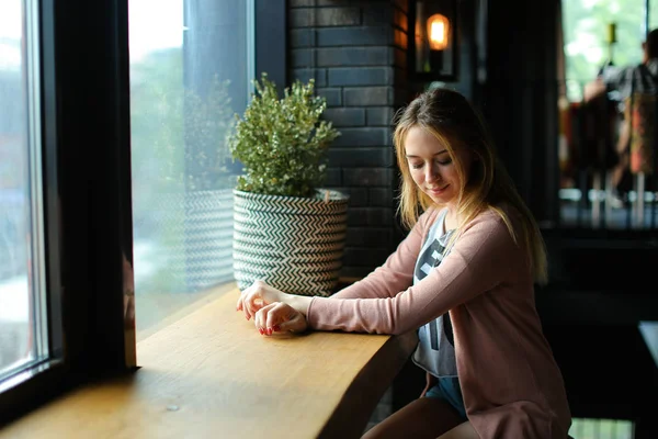Miła kobieta siedzi w pobliżu okna w kawiarni i marzy. — Zdjęcie stockowe