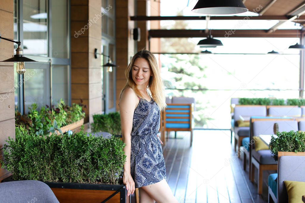 Young woman standing at cafe near green palnts.