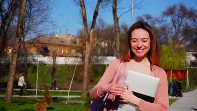 Çok gülümseyen kız smartphone ve dizüstü bilgisayar ile park içinde gezinme.