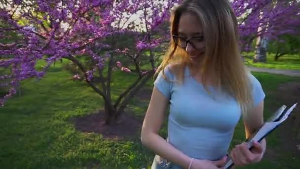 Landschap ontwerper wandelen met documenten in de buurt van bloeiende boom, slow-motion. — Stockvideo