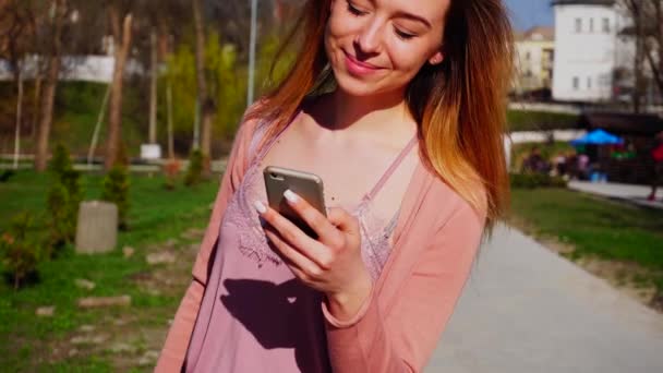 Ragazza digitando messaggio da smartphone vicino al parco al rallentatore . — Video Stock