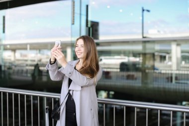 Güzel işkadını smartphone valiz ve Havaalanı yakınında selfie yapma.