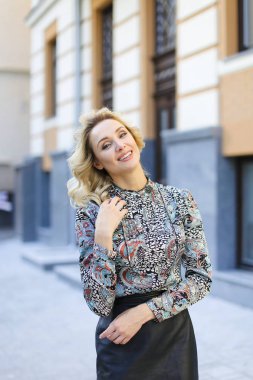 Arka planda bina ve deri etek giyen yakın duran büyüleyici kadın.