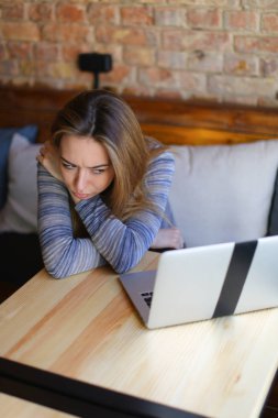 Rahat coffee House yakınındaki cam fincan cappuccino ile ahşap masa oturma ve dizüstü bilgisayar kullanarak genç kadın.