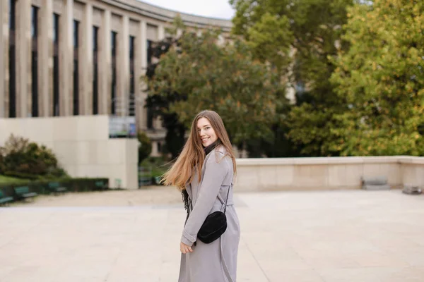 Mädchen läuft in der Nähe eines Gebäudes durch die Stadt und trägt grauen Mantel. — Stockfoto
