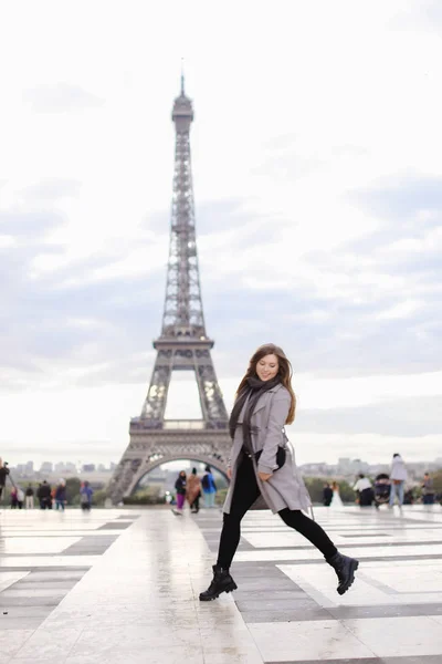 Jocund nő a szürke kabátot, ugrás a párizsi Eiffel-torony közelében. — Stock Fotó