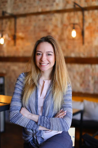 Chica satisfecha sentada cerca de la mesa en acogedora cafetería con un interior inusual . — Foto de Stock