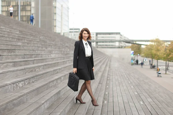Όμορφη επιχειρηματίας που πηγαίνει κάτω σε σκάλες σε ψηλά κτίρια φόντο. — Φωτογραφία Αρχείου