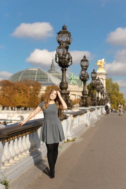 Güzel kadın kişi Fransa sokak vintage ışıkları ve beyaz beton korkuluk, gri elbiseli.