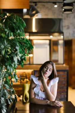 Güzel fotoğraf modeli café'de dinlenme ve gümüş yüzük ile beyaz bluz giyiyor.