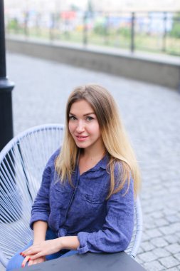 Kafede oturan ve mavi gömlek giymiş genç kadın.