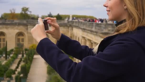 Turista femenina tomando fotos del jardín de Versalles por teléfono inteligente . — Vídeo de stock