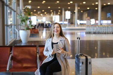 Havaalanı hall yanında valiz tablet ile internet kullanan kız.