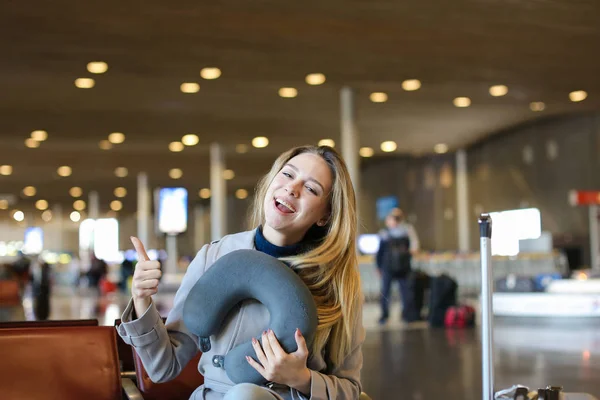 Ładna kobieta siedzi z Poduszka pod szyję i walizka w poczekalni Lotnisko. — Zdjęcie stockowe