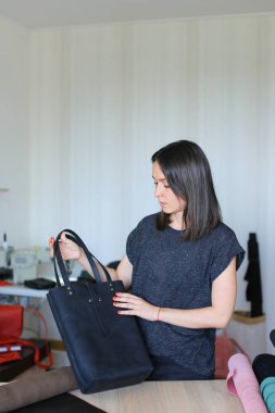 Siyah el yapımı deri çanta, atelier ile duran kadın.