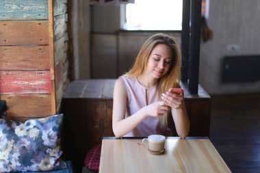 Kahve ile rahat kafede oturan ve fotoğraf bellek için poz genç kadın.