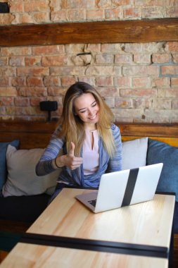 Güzel erkek beyaz dizüstü bilgisayar ve samimi kafede kahve ahşap masa oturma.