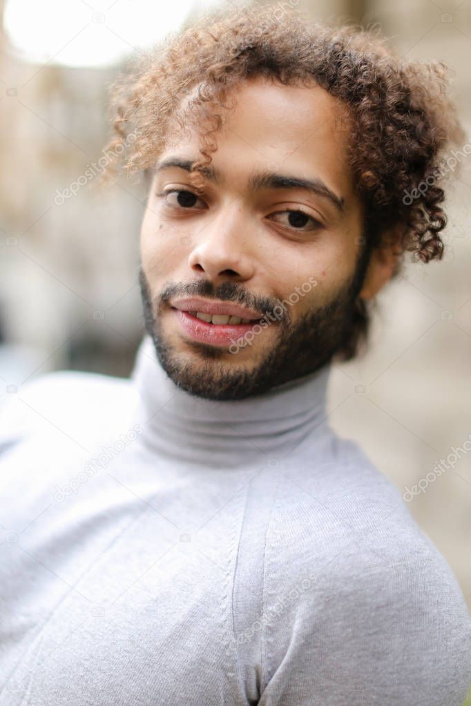 Close up face of afro american young male person with brown curly hair.