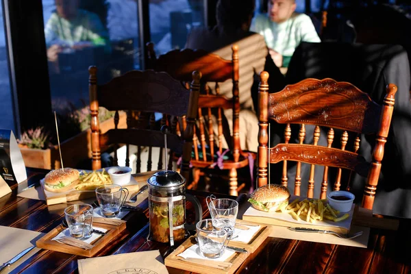 Té caliente en cerveza en la mesa y gamburger de comida rápida y papas fritas en la cafetería  . — Foto de Stock