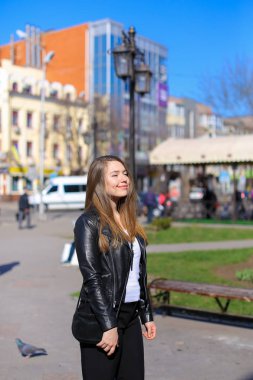 Şehirde yürüyüş ve deri ceket giymiş mutlu kadın kişi.